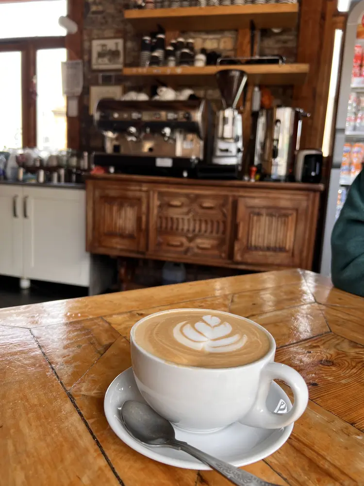 Flat white with latte art on a timber counter in front of the espresso machine
