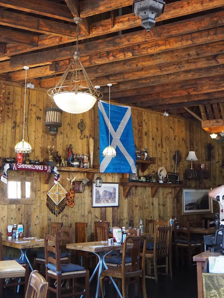 Wood-lined dining room with a Saltire flag hanging beside Ottoman lanterns and dried chillies
